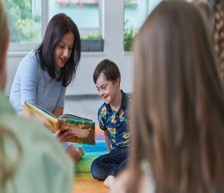 Teacher reading a book to attentive children in a classroom.
