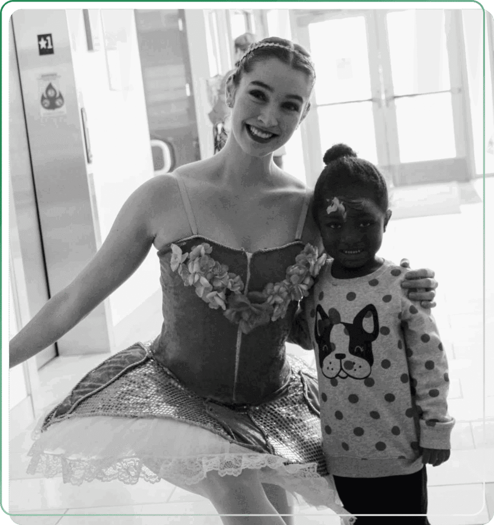 A ballerina in costume poses with a child wearing a Minnie Mouse sweater.